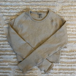 Beige ribbad träningstopp från Aimn - Säljer en beige croppad träningstopp från Aimn med ribbad struktur och rund hals. Tröjan har långa ärmar och är perfekt för träningen 🫶🏼 Aldrig använd, inga defekter! Nypris 549 kr
