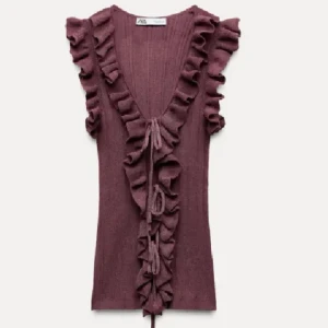 volangtop från Zara - Supersöt topp från Zara med volanger längs axlar och framstycke. Toppen har djup v-ringning, snörning framtill och är ärmlös.