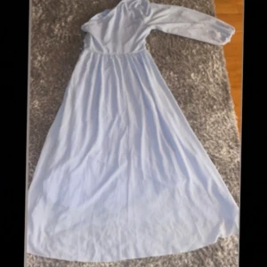 Ljusblå långklänning med lång ärm - Säljer en ljusblå långklänning med lång ärm och rund hals. Klänningen har en mjuk och slät yta, troligtvis i polyester eller bomull. Den har en enkel och stilren design utan mönster eller detaljer, perfekt för dig som gillar minimalistiskt och elegant.