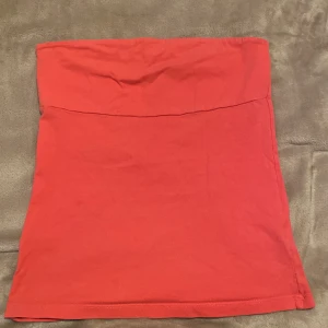 Röd tub topp från Gina Tricot - Enkel och snygg röd tub topp från Gina Tricot i stretchig bomull. Toppen är kort och har en rak passform som sitter tajt runt kroppen. Perfekt att styla med en crop top eller oversized hoodie för en trendig look.