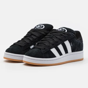 Adidas Campus svart/vit sneakers 38⅔ - Säljer ett par Adidas Campus sneakers i svart mocka med vita ränder och logga på plösen.  Perfekta för dig som gillar en clean och tidlös streetstil.