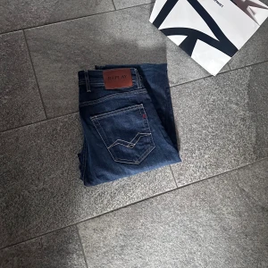 Replay Grover raka jeans blå 29/32 - Snygga mörkblå jeans från Replay, modell Grover med straight fit. Klassisk femficksdesign, kontrastsömmar och läderpatch bak i midjan. Tillverkade i slitstarkt jeanstyg som sitter skönt och passar till det mesta.