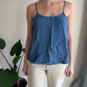 Blå jeanstopp från Koala Bay - Säljer en blå jeans topp från Kala Bay (Australian brand) med tunna axelband och avslappnad passform. Toppen har en enkel, stilren design och är tillverkad i ett mjukt bomullsliknande material. 
