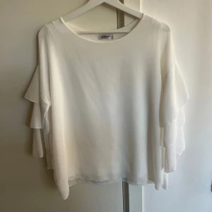 Vit blus  - Vit blus med volang ärmar. Blusen är i strl M/L och kommer från ”Audrey”. Mycket bra skick! Inga fläckar.