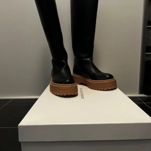 By Malene Birger stövlar  - Snygga svarta stövlar i skinn med en robust brun sula. Perfekta för alla säsonger med en stilren design som passar till många outfits. Använda ett fåtal ggr! Ny pris 5599kr