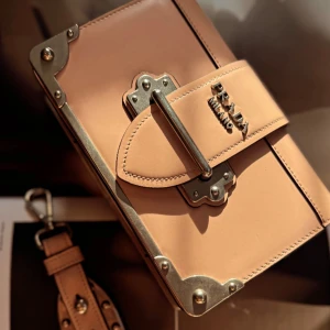 Prada Milano Väska - Snygg  axelväska/ chlutch från Prada med metallbeslag och kedja i silverfärg. Väskan har en boxig form, coola nitar och detaljer, samt logotypen 'PRADA MILANO' på framsidan. Tillverkad i slätt skinn med robust känsla och unika metalldetaljer.