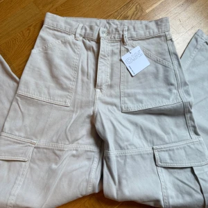 Beiga Carin Wester byxor  - Snygga beiga cargopants från C.W. med stora fickor på benen. Byxorna har raka ben, bälteshällor och är tillverkade i mjuk material. Perfekta för en avslappnad och trendig look. Oanvända med prislapp kvar. Storlek 38 men skulle säga att de är en mindre M. Nypris 800kr🩷