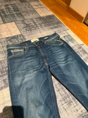 Replay Grover Hyperflex jeans blå - Replay Grover Hyperflex jeans i klassisk blå tvätt. Modellen har rak passform. Jeansen är tillverkade i stretchigt denim för extra komfort och har diskreta slitningar. Jeansen har använts ett fåtal gånger (3-4 gånger), märks inte att de har använts.