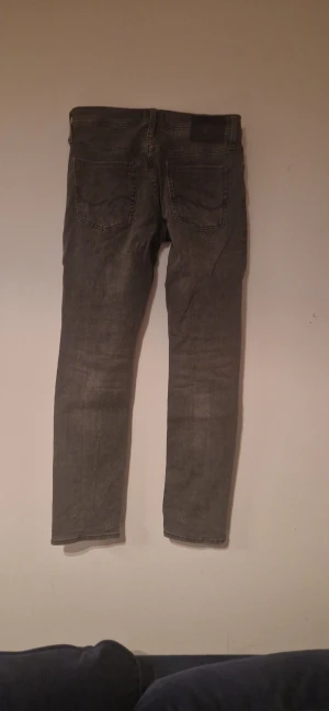 Grå slim jeans från Jack & Jones - Säljer ett par grå slim fit jeans från Jack & Jones, modell Slim Glenn. Jeansen har klassisk femficksdesign, snygga bakfickor med broderad detalj och är tillverkade i mjukt denimtyg. Perfekt för dig som gillar en smalare passform och stilren look. Slim/skiny 