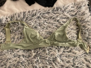 Ljusgrön ribbad bikiniöverdel - Snygg ljusgrön bikiniöverdel med ribbad struktur och guldfärgade spännen. Triangelmodell med breda axelband som går att justera för bästa passform. Perfekt för strandhäng och poolparty i sommar! Materialet känns mjukt och följsamt mot huden. Fler bilder kan skickas och pris kan självklart diskuteras!🥰 Jag har användt den fåtal gånger. 