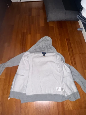 Grå hoodie från Polo Ralph Lauren - Säljer en grå hoodie från Polo Ralph Lauren i storlek L (14-16). Tröjan har huva, hel dragkedja framtill och två fickor. Klassisk design med Polo-logga broderad på bröstet. Perfekt för chill dagar och enkel att matcha med jeans eller joggers.