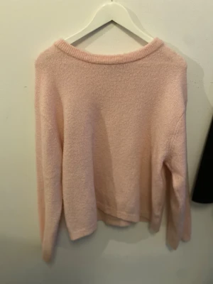 Ljusrosa stickad tröja - Mysig ljusrosa stickad tröja med rund hals och långa ärmar. Perfekt för att hålla sig varm under kyliga dagar. Enkel och stilren design som är lätt att matcha med dina favoritjeans eller kjol.