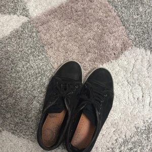 Svarta sneakers från Lanvin - Svarta sneakers från Lanvin med rund tå och platt vit sula. Skorna har snörning och är tillverkade i skinn med detaljer i mocka. Haft länge men har mycket kvar att ge 