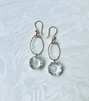 Guldiga örhängen med kristallhänge, stål - Stilrena örhängen med tunna guldiga ovala ringar och stora, facetterade klara kristallhängen. De har en elegant och modern look som verkligen fångar ljuset. Perfekta för dig som vill sticka ut med något unikt och glittrande.stål