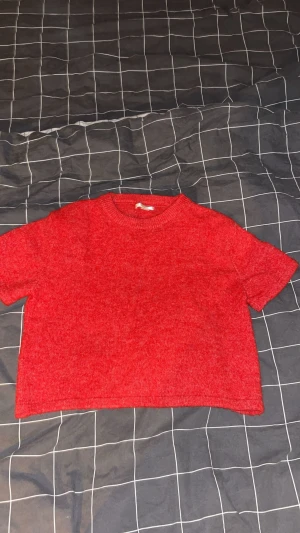 Röd croppad stickad topp passar S - Säljer en röd croppad stickad topp med korta ärmar och rund hals. Perfekt för dig som gillar enkel men snygg stil. Tjockt och mjukt material 