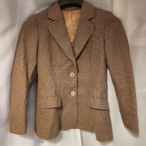 Kavaj - Fodrad brun hundtandsmönstrad kavaj i mycket bra skick. Två knappar och fickor framtill.