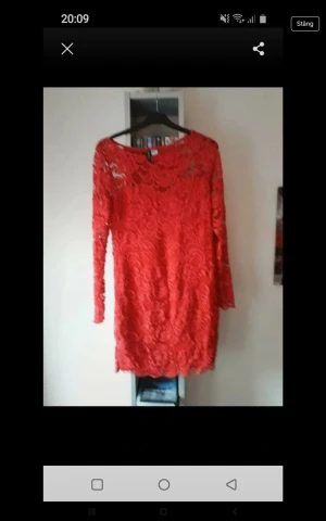 Röd spetsklänning med lång ärm - Snygg röd kortklänning i spets med långärmad design och rund halsringning. Klänningen har ett vackert blommigt spetsmönster och är figurnära. Perfekt för dig som vill sticka ut med en färgstark look.