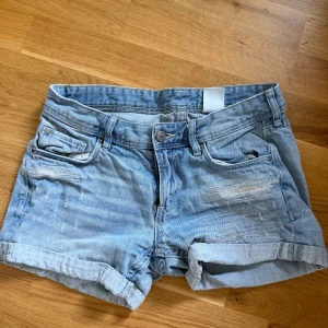 Ljusblå jeansshorts från H&M - Säljer ett par ljusblå jeansshorts från H&M i storlek 158. De har slitna detaljer och uppvikta benslut.