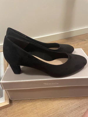 Svarta klackskor från Tamaris - Snygga svarta klackskor från Tamaris i storlek 39. Skorna är använda 1 gång. Nypris 699kr