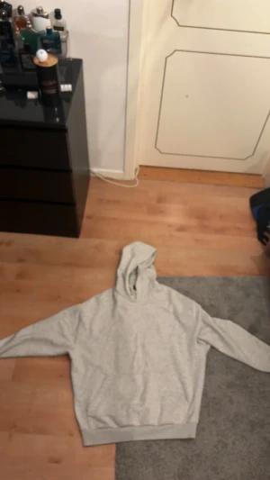 Ljusgrå hoodie från ASOS DESIGN - Säljer en ljusgrå hoodie från ASOS DESIGN med klassisk huva och snörning. Tröjan har lång ärm, ribbade muddar och är tillverkad i mjuk bomullsmix. Perfekt för chill dagar och enkel att matcha med jeans eller joggers.