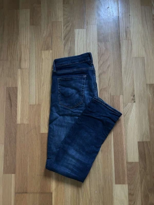 Jack & Jones Super Stretch jeans blå - Mörkblå jeans från Jack & Jones med superstretch för extra komfort. Klassisk femficksdesign, raka ben och snygga slitningar framtill. Passar dig som vill ha jeans med lite mer flexibilitet och stilren look.