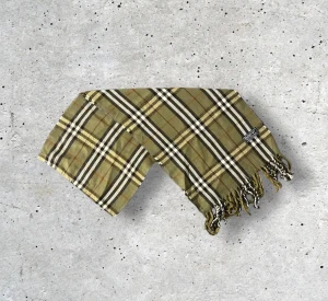 Burberry halsduk Olivgrön - Säljer en tidlös Burberry-halsduk i en djup, mörkgrön färg med det ikoniska rutmönstret. Tillverkad i 100% mjuk och värmande ull som känns lyxig, håller formen väl och ger en exklusiv helhetskänsla. En perfekt accessoar som ger en subtil men sofistikerad färgton till både vardags- och kvällsoutfits.  🧵 Skick: Mycket fint skick, varsamt använd 🌟 Känsla: Mjuk, varm och följsam 📦 Frakt: Skickas tryggt inom 24h 📏 Mått: Längd-150cm, Bredd-30cm Pris kan diskuteras!