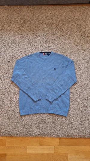 Blå stickad tröja från CHAPS - Snygg skön blå stickad tröja från CHAPS i storlek M. 100% bomull. Använd fåtal gånger och skicket är i princip som ny. Inga defekter eller slitningar finns. Passar riktigt bra nu under vintern och Jul. Skick: 8/10