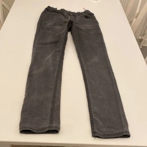 Levi's 512 Slim Tapered grå jeans - Snygga grå Levi's 512 Slim Tapered jeans BARN med klassisk femficksdesign och smal passform som smalnar av nedtill. Jeansen har en mörkgrå tvätt med subtila slitningar och är tillverkade i mjukt jeansmaterial. Obs: lagning i skrevet. Stl 12A, 152cm. Innermåt ben 68cm.