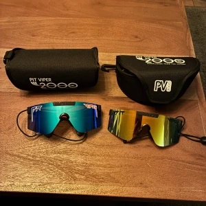 Äkta Pit Viper 2000 solglasögon! - Två par Pit Viper 2000 sportglasögon med spegelglas, en med blå/grön lins och röda/blå skalmar, den andra med gul/orange lins och svarta skalmar. Nästan oanvända så inga skavanker, ny pris runt 1000kr på båda!