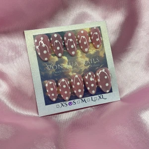 Dotz (S);Short Almond;Curved - Snygga handgjorda press-on naglar i kort mandelform med ljusrosa bas och vita prickar. Perfekt för dig som vill ha unika och trendiga naglar utan att gå till salong. Kommer i S: 15 mm, 11,5 mm, 12 mm, 11 mm, 9 mm , och är enkla att applicera.