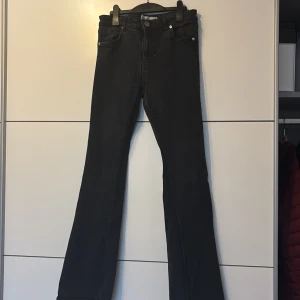 Svarta bootcut jeans från Amisu, strl 38 - Svarta jeans från Amisu i storlek 38 med klassisk femficksdesign och snygg bootcut-passform. Jeansen har hög midja och är tillverkade i ett mjukt bomullsmaterial med lite stretch för extra komfort. Perfekt för dig som gillar en stilren look med lite utsvängda ben.