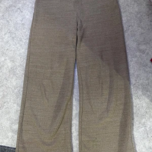 Beige ribbade byxor - Snygga beige stickade byxor med ribbad struktur och rak passform. De har en mjuk och skön känsla, perfekt för chill dagar. Midjan är elastisk och byxorna har en loose fit som ger en avslappnad vibe. Materialet är stickat och färgen är neutral beige.