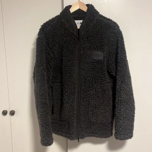 Svart/Grå fleecejacka från NN07 - Säljer nu denna fleecejack från NN07 i stl:L. Är inte alls använd särskilt mycket och därför mycket bra skick. Jag är 192 cm och den sitter precis på mig. Vid fråga är det bara och skriva 