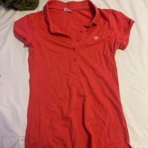 Röd/rosa skjorta  - Säljer en röd/rosa kort skjorta från Gina Tricot i piké-stil med krage och knappslå framtill. 