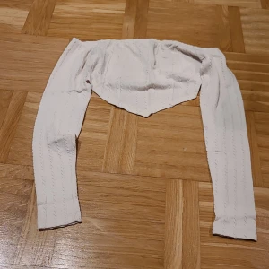 Vit offshoulder croppad topp från SHEIN - Säljer en vit offshoulder topp från SHEIN i storlek XS. Toppen är croppad med långa ärmar och har ett ribbat mönster som ger en snygg struktur. Materialet är mjukt och stretchigt, perfekt för att skapa en cool och trendig look.