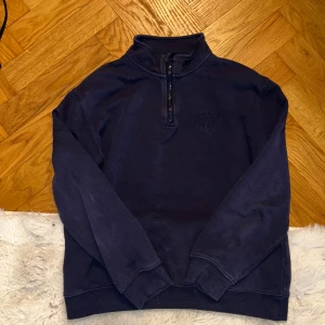 Mörkblå half zip tröja  - Snygg mörkblå långärmad tröja från H&M med half zip och broderat NYC-emblem på bröstet. Tröjan har en hög krage och är gjord i mjuk bomull, perfekt för chill dagar. Ribbstickade muddar vid ärmslut och nederkant för extra comfort.