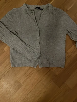 Ljusgrå kofta från 157, XS - Ljusgrå kofta från 157 i storlek XS. Klassisk modell med rund hals, långa ärmar och knappar framtill. Tillverkad i mjukt material med ribbade muddar vid ärmslut och nederkant. Perfekt att slänga över en t-shirt eller linne. Pris går att diskuteras!