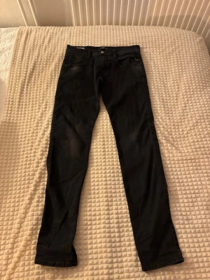 Replay svarta jeansbyxor 29/32 - Säljer ett par svarta Replay jeansbyxor i storlek 29/32. Byxorna har klassisk femficksdesign, raka ben och Replay-logga på bakfickan. Materialet är mjukt jeans-tyg och färgen är mörk svart med lätt tvättad look.