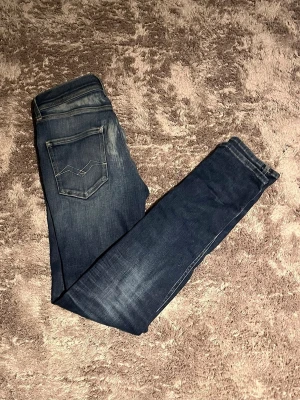 Mörkblåa slim fit jeans från Replay  - Säljer ett par mörkblå Replay jeans  med snygga slitningar!