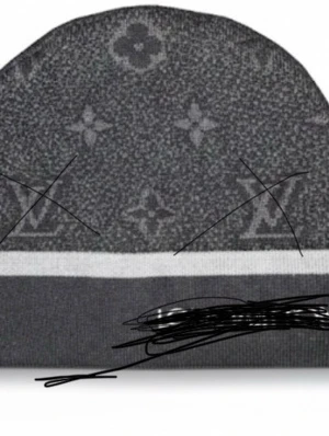 Grå mönstrad mössa - Säljer en grå mössa med ett diskret mönster och en vit rand längst ner. Perfekt för kalla dagar och ger en stilren look till din outfit.