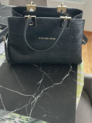 Svart handväska från Michael Kors - Säljer en hitte på mk väska med tillhörande axelband väldigt rymlig