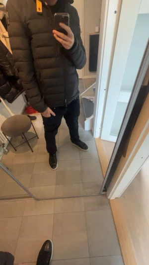 Svart pufferjacka från Parajumpers - Säljer en svart pufferjacka från Parajumpers med gul detalj vid kragen och dragkedja framtill. Jackan är superlätt och har en snygg quiltad design samt praktisk innerficka märkt 'Security Pocket'. Perfekt för kalla dagar och riktigt stilren.