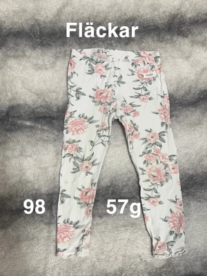 Blommiga leggings från Newbie - Supersöta vita leggings med rosa och grönt blommönster från Newbie  gulligt print. Resår i midjan för skön passform.🌸 Fläckar. Storlek 98