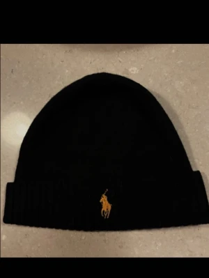 Ralph Lauren mössa  - Ralph Lauren mössa i toppenskick, knappt använd. Svart med en guldig logga!