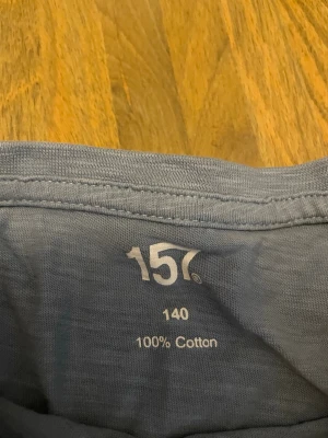 Blå basic t-shirt från 157 - En enkel sopblå t-shirt från 157 i 100% bomull. Klassisk rund halsringning och korta ärmar. Perfekt till chill vardagsstil och lätt att matcha med jeans eller shorts. En fläck därav priset 