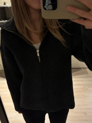 Svart stickad half zip från Bik Bok - Mysig svart stickad tröja från Bik Bok i ribbat material. Tröjan har en hög krage och half zip-dragkedja framtill. Perfekt till höst och vinter, med lång ärm och lätt att styla med allt.