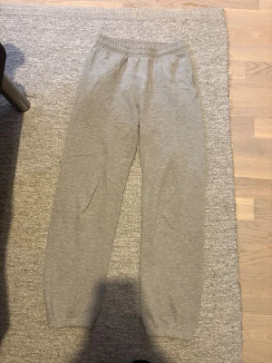 Dam gråa mjukisbyxor  - Säljer ett par klassiska grå mjukisbyxor med resår i midjan och raka ben i storlek 150/XXS. Byxorna har sidofickor och är gjorda i mjukt bomullsmaterial. Perfekta för chill dagar eller när du vill vara extra bekväm.
