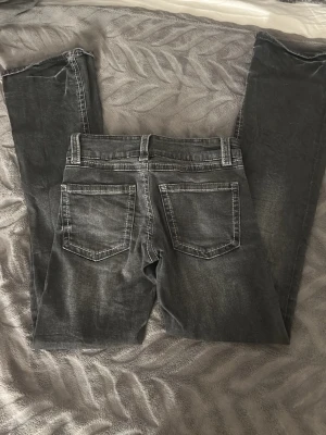 Svarta jeans från Gina Tricot, stl 152 - Säljer ett par svarta jeans från Gina Tricot i storlek 152. Jeansen har raka ben, dubbla knappar i midjan och klassiska bakfickor. Snygga kontrastsömmar och justerbar midja på insidan. Perfekta till en chill vardagslook.