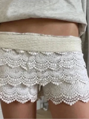 Vita spets-shorts med volang - Ett par vita spets-shorts som är superfräscha och perfekta för sommaren. De är sköna att ha på sig och sitter snyggt utan att kännas för tajta. Lätta att matcha med typ ett linne eller en t-shirt för en chill men ändå fin outfit.