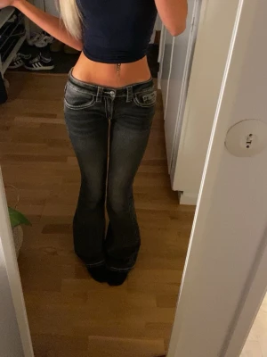 Lågmidjade bootcut jeans Gina 14+ - Säljer ett par mörk gråa bootcut jeans med tydliga vita kontrastsömmar och låg midja ifrån Gina 14+ i storlek xs tall. Nästan aldrig använda och är helt slutsålda 